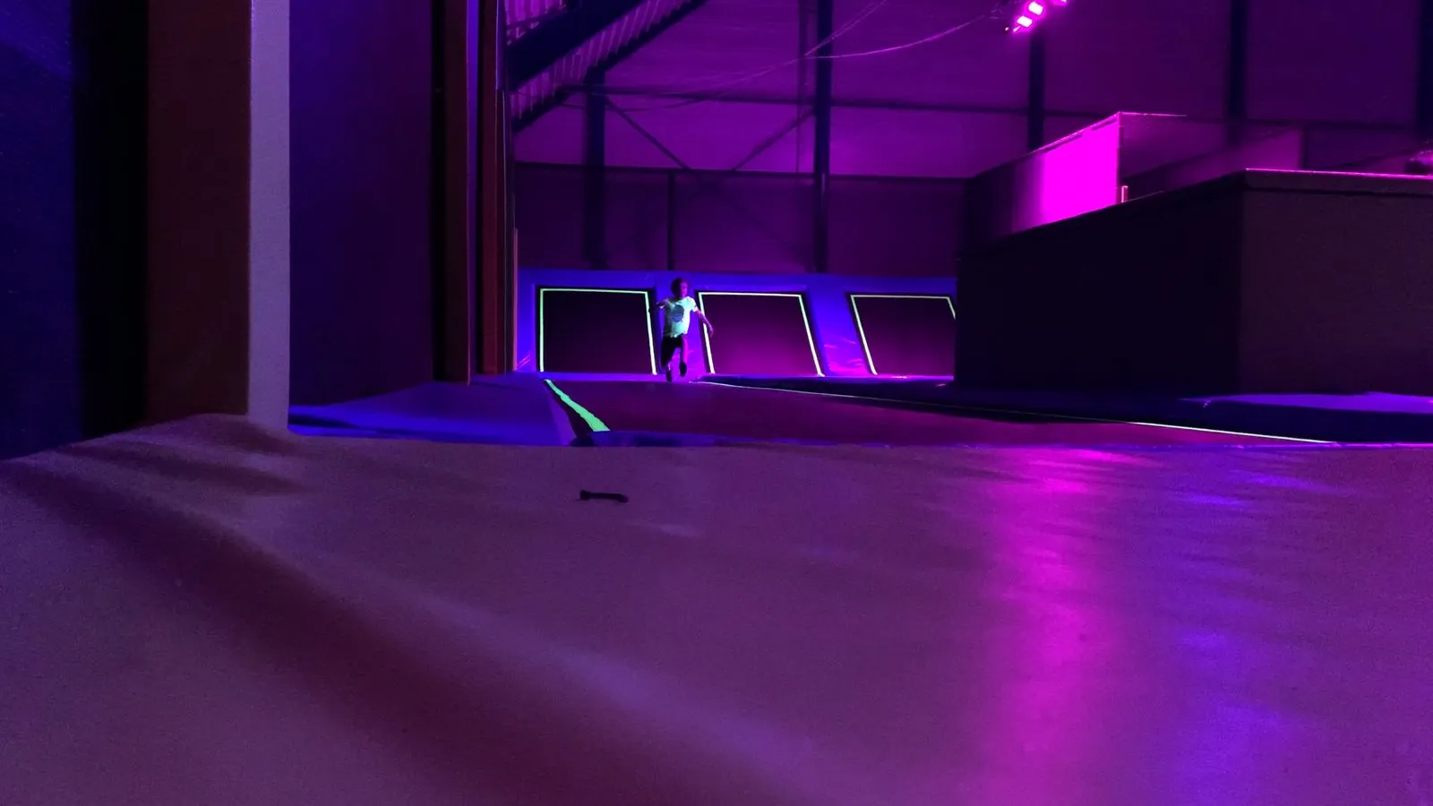 Sauteur en plein saut dans le trampoline park éclairé en violet